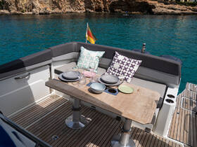 A beautifully arranged dining area on a boat, featuring a wooden table set with plates and glasses, perfect for enjoying meals and cocktails while surrounded by stunning turquoise waters.