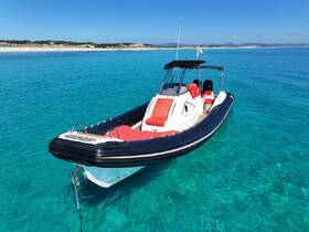 A sleek speedboat anchored in crystal clear waters, showcasing its vibrant red and black design against a stunning coastal backdrop.
