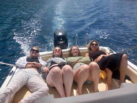 A group of friends relaxes and sunbathes on a boat, enjoying a perfect day on the water — ideal for summer outings and bonding moments.