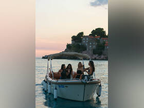 A group of friends enjoys a sunset celebration aboard a boat, toasting with cocktails against a picturesque coastal backdrop.