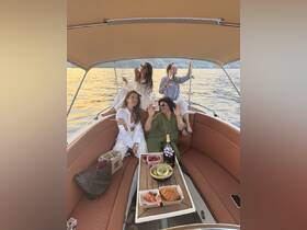 A lively group of friends enjoys a sunset celebration on a yacht, complete with cocktails and delicious snacks — perfect for memorable outings on the water.