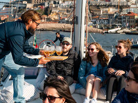 A lively group enjoys cocktails aboard a sailboat, creating a perfect atmosphere for celebration and relaxation on the water.