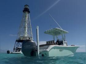 A sleek speedboat anchored near a historic lighthouse, showcasing the perfect blend of adventure and scenic beauty in open waters.