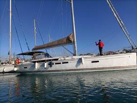 A sailor poses on the deck of a beautiful yacht in a marina, showcasing the vibrant atmosphere of sailing adventures.