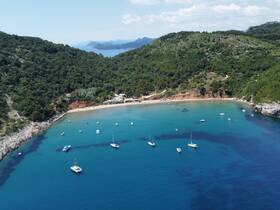 A stunning aerial view of a tranquil bay surrounded by lush greenery, featuring several boats anchored in the clear blue waters — an ideal destination for relaxation and exploration.