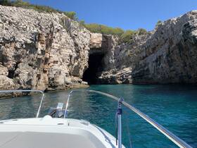 A stunning view of a rocky coastline and cave entrance as seen from a boat, showcasing the natural beauty of the area — perfect for exploring hidden gems along the shore.