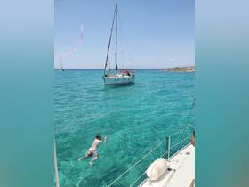 A swimmer enjoys the crystal-clear waters while a sailboat with guests is anchored nearby, capturing the essence of a perfect day on the water.