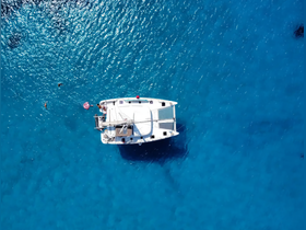 An aerial view of a catamaran anchored in stunning turquoise waters, with swimmers enjoying the refreshing sea — a perfect scene for a tropical getaway.
