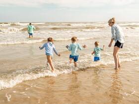 A joyful family enjoys a day at the beach, with children splashing in the waves and creating lasting memories in the sun.