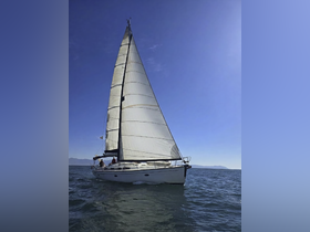 A beautiful sailboat glides through the water with crew members on deck, showcasing the thrill of sailing on open waters.