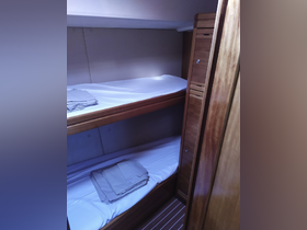 Interior view of a boat cabin featuring two bunks with fresh linens, ideal for comfortable overnight stays while cruising.