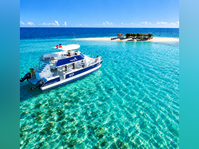 A stunning aerial view of a VIP catamaran cruising through crystal-clear waters, showcasing the beauty of the surrounding tropical paradise.