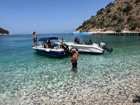 A lively group enjoys a sunny day at the beach, with one person swimming and others relaxing on the boat — a perfect scene for summer fun on the water.