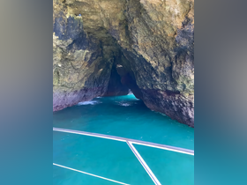 A stunning view of a cave entrance surrounded by vibrant turquoise waters, perfect for exploring hidden gems during a boating adventure.