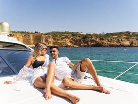 A couple enjoys a relaxing moment sunbathing on the deck of a yacht, surrounded by stunning ocean views — perfect for romantic getaways or summer adventures.