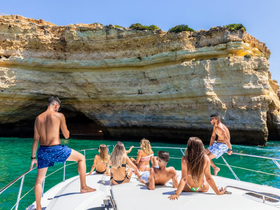 A lively group enjoys a sunny day on a boat, taking in the stunning coastal scenery — perfect for summer adventures and memorable outings.