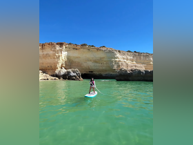 A paddleboarder navigates the serene waters near stunning cliffs, showcasing the beauty of outdoor adventures and coastal exploration.