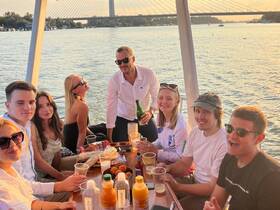A lively group enjoys drinks and snacks aboard a pontoon boat at sunset, creating unforgettable memories on the water.
