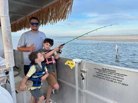 A family enjoys a fishing trip on the water, with kids actively participating and catching fish — a perfect bonding experience for outdoor enthusiasts.