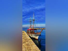A stunning view of a traditional yacht docked at the harbor, showcasing its elegant structure against a vibrant blue sky.