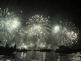 A stunning display of fireworks lights up the night sky, viewed from a boat with silhouettes of guests enjoying the celebration — a perfect backdrop for festive occasions on the water.