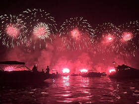 A stunning display of fireworks lights up the night sky as guests enjoy the view from their boats, creating a vibrant atmosphere for celebrations on the water.