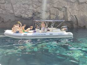 A lively group enjoys a day on the water aboard a boat, surrounded by stunning rock formations — perfect for adventure and exploration.