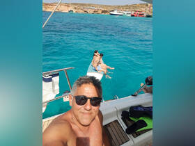 A joyful moment captured with a couple enjoying the turquoise waters while lounging on a paddleboard, showcasing the perfect summer getaway on the boat.