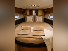 Cozy interior of a boat cabin featuring a comfortable bed adorned with decorative pillows and neatly arranged towels, perfect for a relaxing getaway on the water.