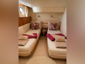 Cozy interior of a boat cabin featuring twin beds adorned with decorative pillows and neatly arranged towels, perfect for relaxing after a day on the water.