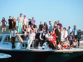 A large group gathers on the deck of a boat for a joyful celebration, showcasing family and friends in a picturesque setting — perfect for weddings or special events on the water.