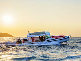 A sleek speedboat glides through the water at sunset, showcasing its elegant design and vibrant seating — perfect for thrilling adventures on the open sea.
