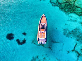 A stunning aerial view of a sleek speedboat gliding over crystal-clear turquoise waters, showcasing the beauty of a perfect day on the water.