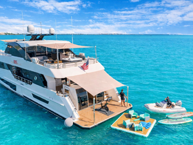 A stunning aerial view of a luxurious yacht anchored in crystal-clear waters, featuring guests enjoying water activities and lounging on a floating mat — perfect for summer adventures.