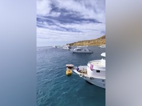A scenic view of multiple yachts anchored in calm waters, showcasing a tranquil boating environment against a backdrop of cliffs.