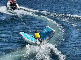 A child enjoys tubing behind a boat, showcasing the thrill of water sports on a sunny day. Perfect for family fun and adventure on the water.