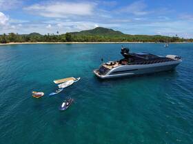 A stunning aerial view of a luxury yacht anchored in crystal-clear waters, surrounded by water toys, perfect for a day of adventure and relaxation.