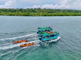 A vibrant glass bottom boat navigates through clear waters, accompanied by kayakers enjoying an exciting day on the water — perfect for adventure seekers and nature lovers.
