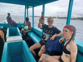 A lively group enjoys their time on a boat, with drinks in hand and a child present, capturing the essence of a fun day on the water.