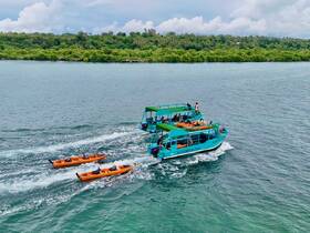 A vibrant glass bottom boat navigates the waters alongside kayakers, showcasing an exciting day of water activities amidst lush greenery.
