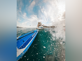 A dynamic shot capturing the excitement of paddleboarding with a splash in the foreground, showcasing the thrill of on-water activities near a boat.