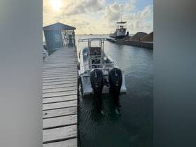 A sleek boat docked at a marina, showcasing its powerful twin outboard engines against a serene waterfront backdrop.
