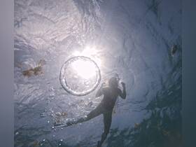 A snorkeler creates a bubble ring while enjoying the underwater experience, capturing the essence of fun and adventure in the ocean.