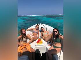 A group of friends relaxes on a boat, enjoying fresh fruit snacks under the sun — a perfect day for fun and relaxation on the water.