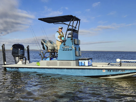 A fisherman navigates a sleek boat on calm waters, showcasing the perfect setup for a day of fishing adventures.
