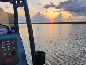 A serene view from the helm of a boat, capturing a stunning sunset over calm waters — perfect for evening cruises.