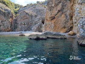 A serene view of a secluded beach surrounded by rocky cliffs and clear turquoise waters, perfect for exploring hidden gems along the coastline.