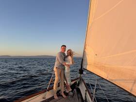 A couple enjoys a romantic moment on the deck of a sailboat at sunset, capturing the essence of love and adventure on the open water.