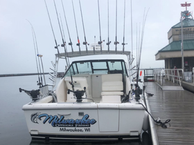 A fishing boat named 'Milwaukee' is docked, equipped with multiple fishing rods, showcasing its readiness for offshore fishing adventures.