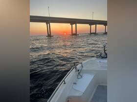 A serene sunset view from the bow of a boat, showcasing the vibrant colors of the sky and the silhouette of a bridge in the background — perfect for peaceful evening cruises.